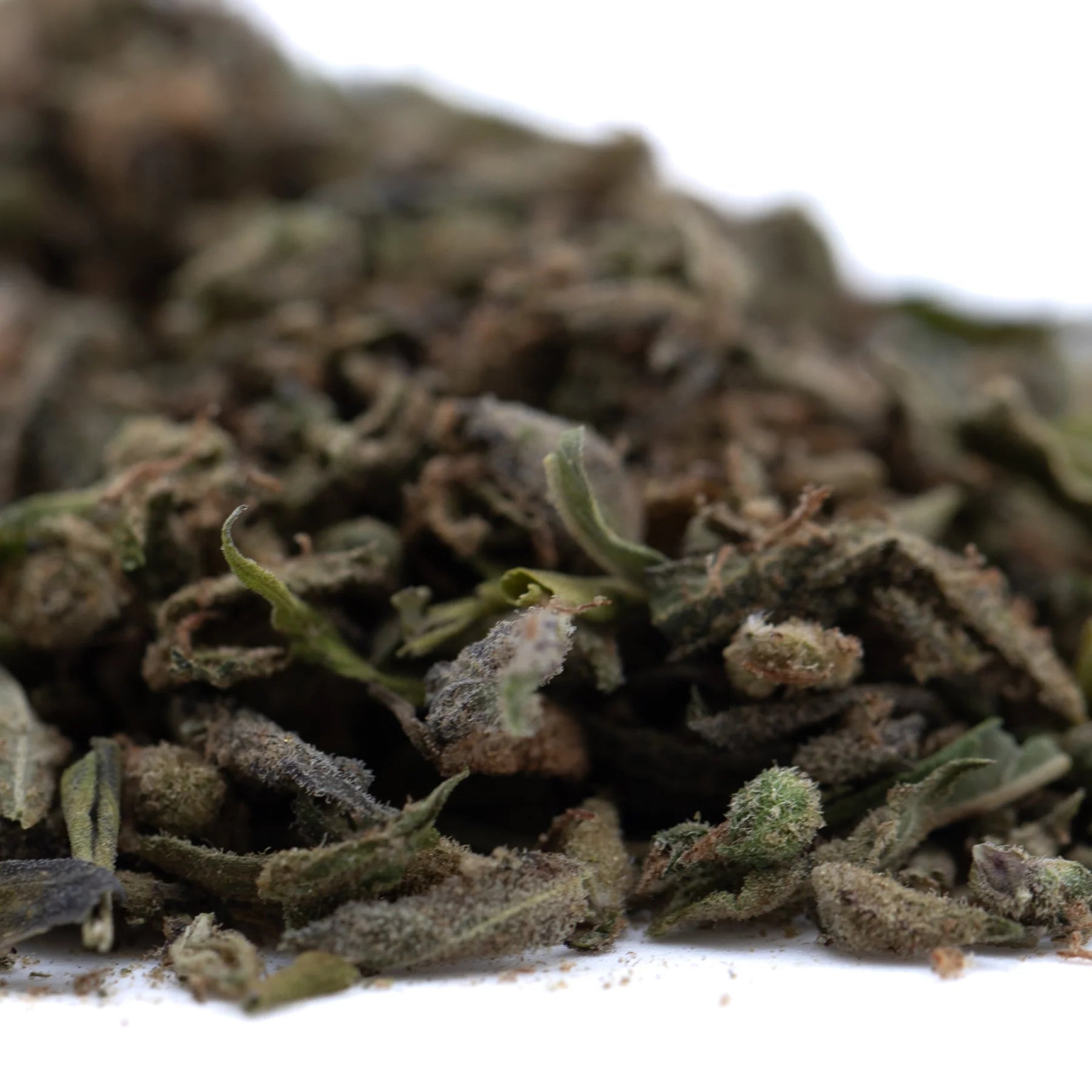 A pile of dried greenish-brown chemdawg x gsc thca trim with pungent garlic aroma for wholesale use