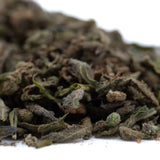 A pile of dried greenish-brown chemdawg x gsc thca trim with pungent garlic aroma for wholesale use