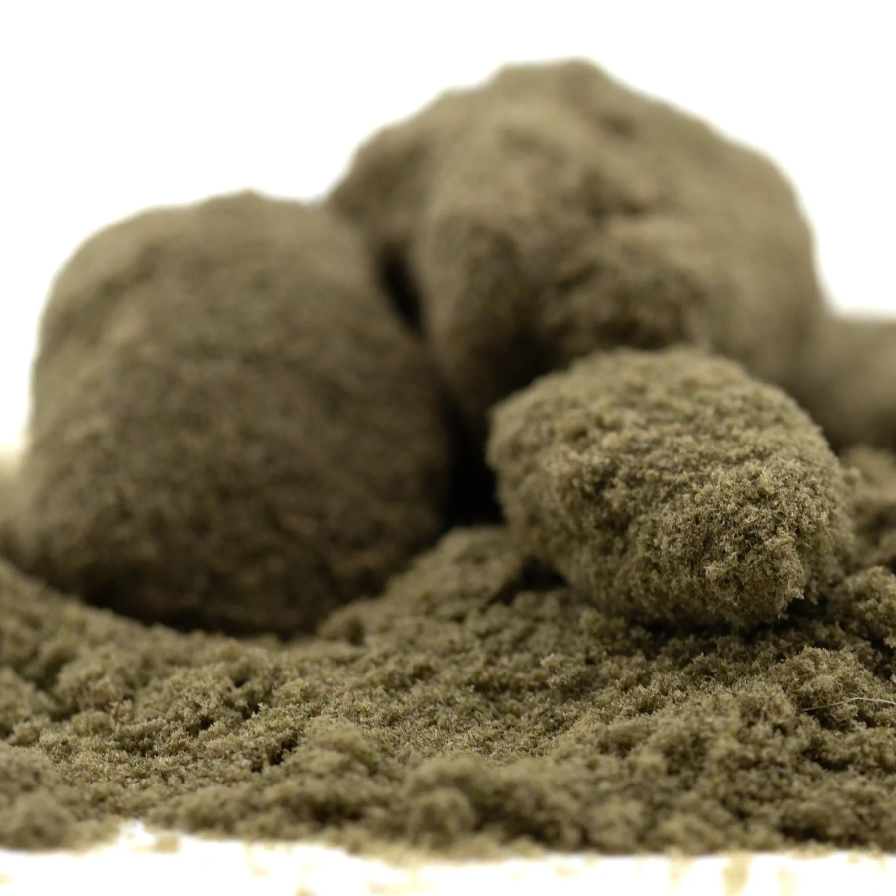 A mound of coarse earthy-brown jelly donut kief with granular texture from louis xiii genetics hemp flower