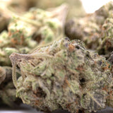 A dense green jokerz candy hemp flower greenhouse smalls bud with white trichomes and hints of orange pistils