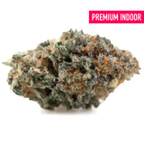 A dense kali snapple indoor thca flower bud with green and orange hues covered in frosty trichomes and tropical pineapple notes