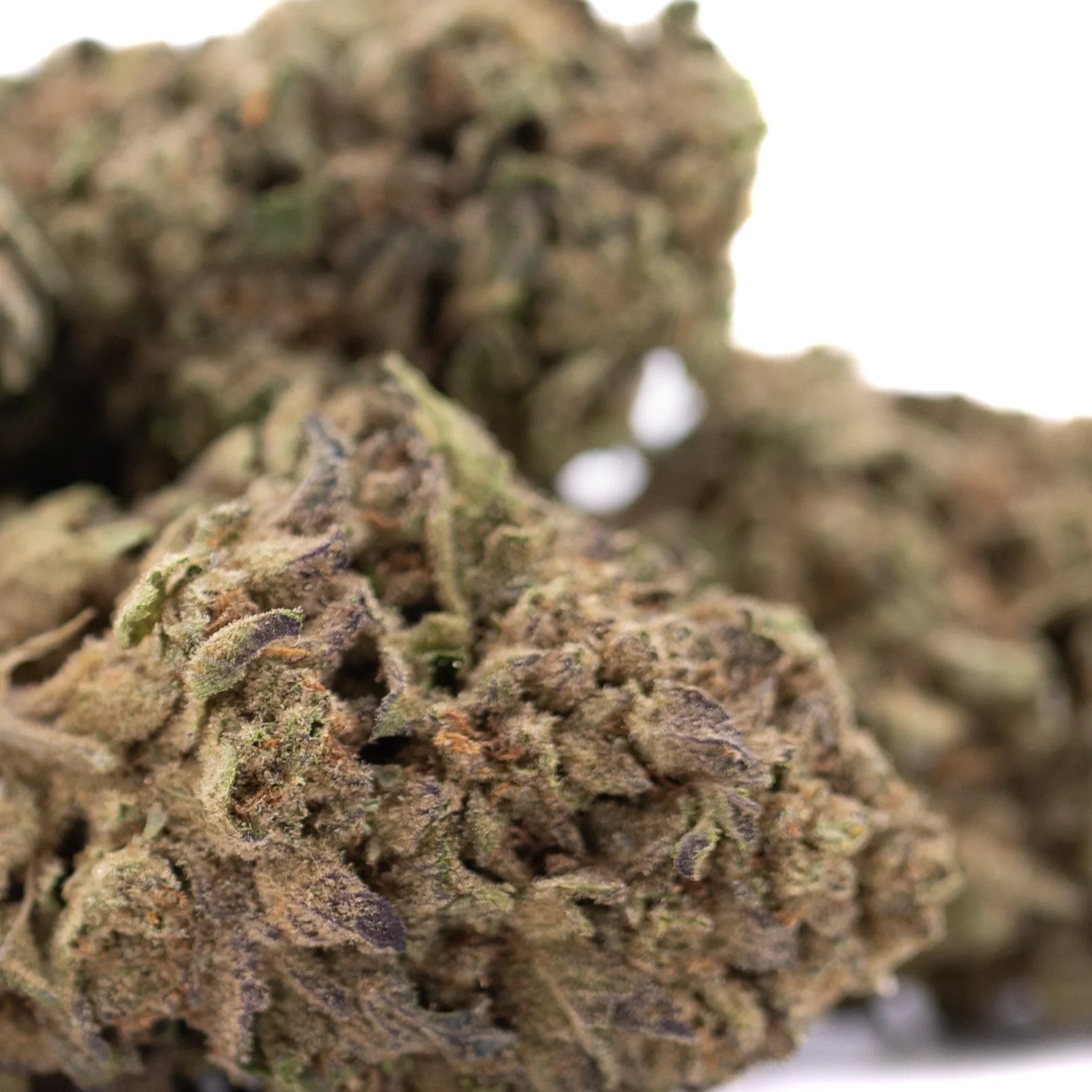 A dense lemon cherry gelato thca hemp flower bud with green and brown hues covered in fine trichomes greenhouse flower