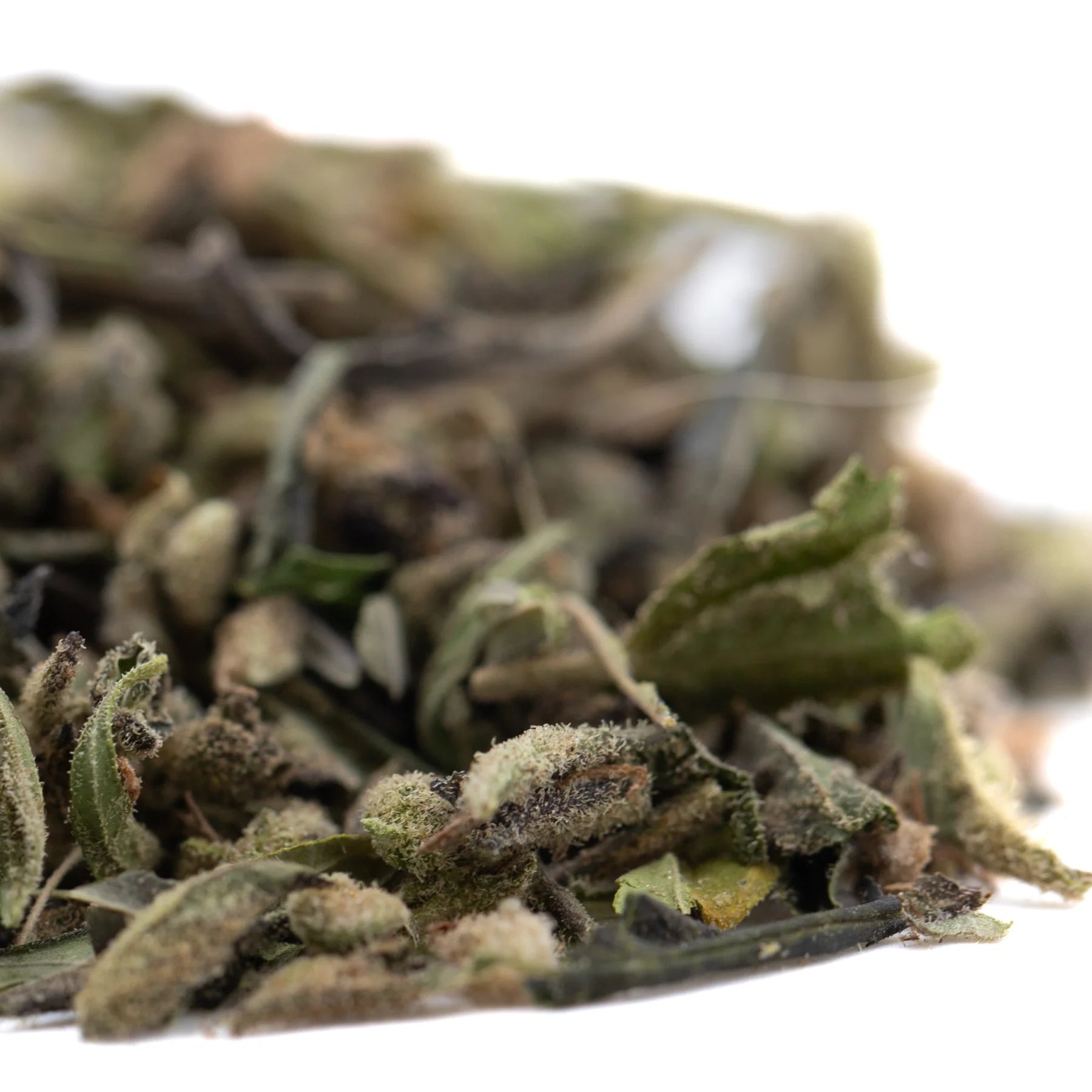 A pile of dried slightly fuzzy green and brown thca trim leaves from mendo breath with hints of vanilla caramel candy