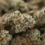 A dense frosty northern lights indoor thca flower smalls bud with green and orange hues