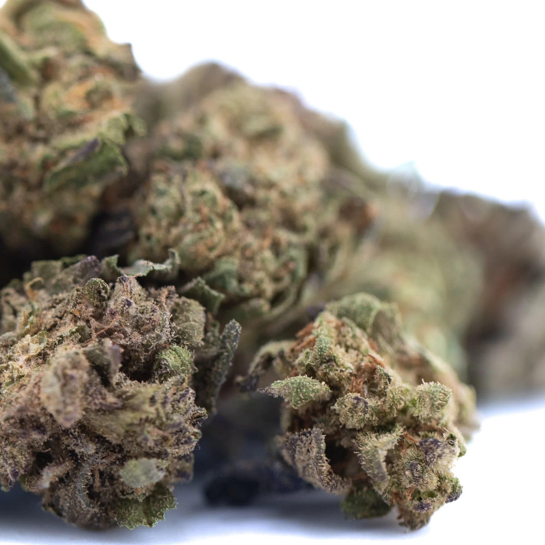 A dense textured hemp flower bud with green and brown hues covered in trichomes from poppin bottlez rozay cake