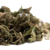 A pile of fuzzy green and brown dried leaves showing pound town full term thca trim wholesale with high cannabinoid content