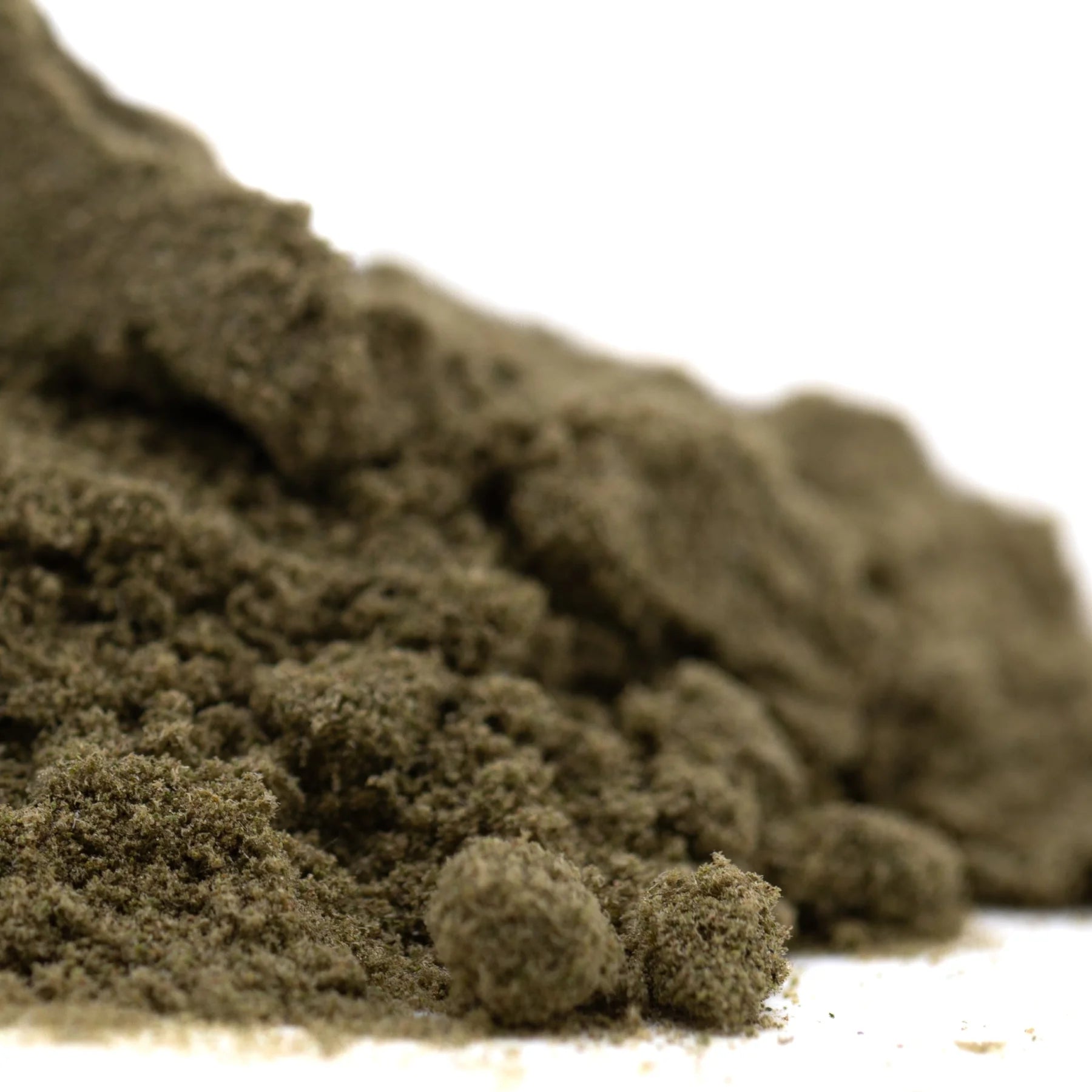 A mound of coarse dark olive-green pound town thca kief with a textured granular surface resembling jet fuel and caramel apple