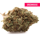 A dense green and brown pure kush’s greenhouse thca flower bud with frosty texture showcasing kush genetics