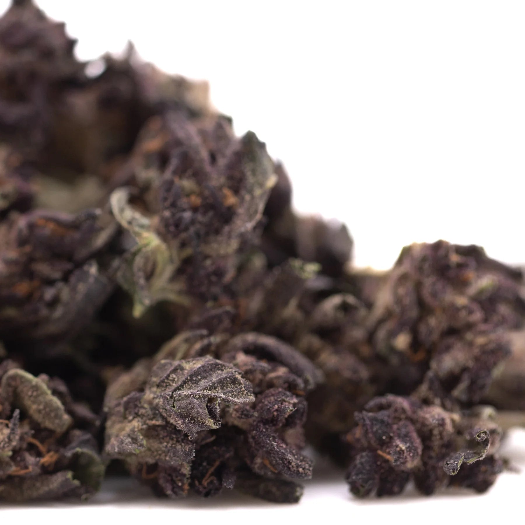 Dark crinkled green and brown dried tea leaves from purple queens thca smalls hemp flower hindu kush blend