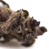 Dense dark purple queen’s thca smalls hemp flower covered in trichomes with greenish pistils for herbal use