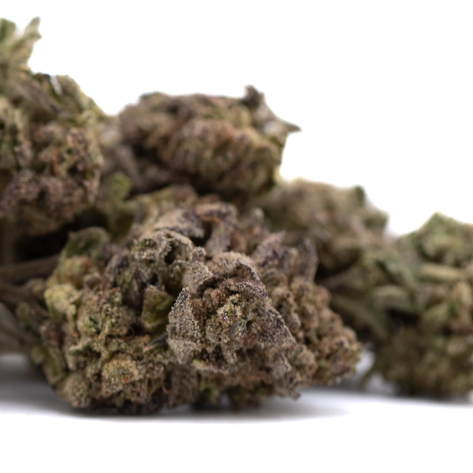 A pile of dense greenish-brown purple wedding cake’s greenhouse thca flower covered in trichomes and textured surface