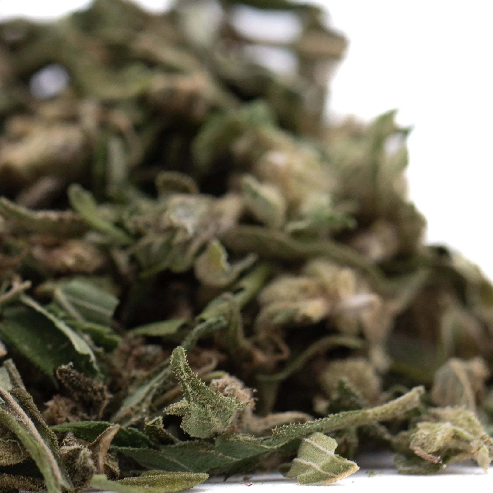 A pile of green and brown full-term thca flower buds covered in fine trichomes with rich terpene profile from indoor cultivation