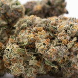 Premium Rozay Cake THCa Flower: Vibrant green bud with orange hues and trichomes