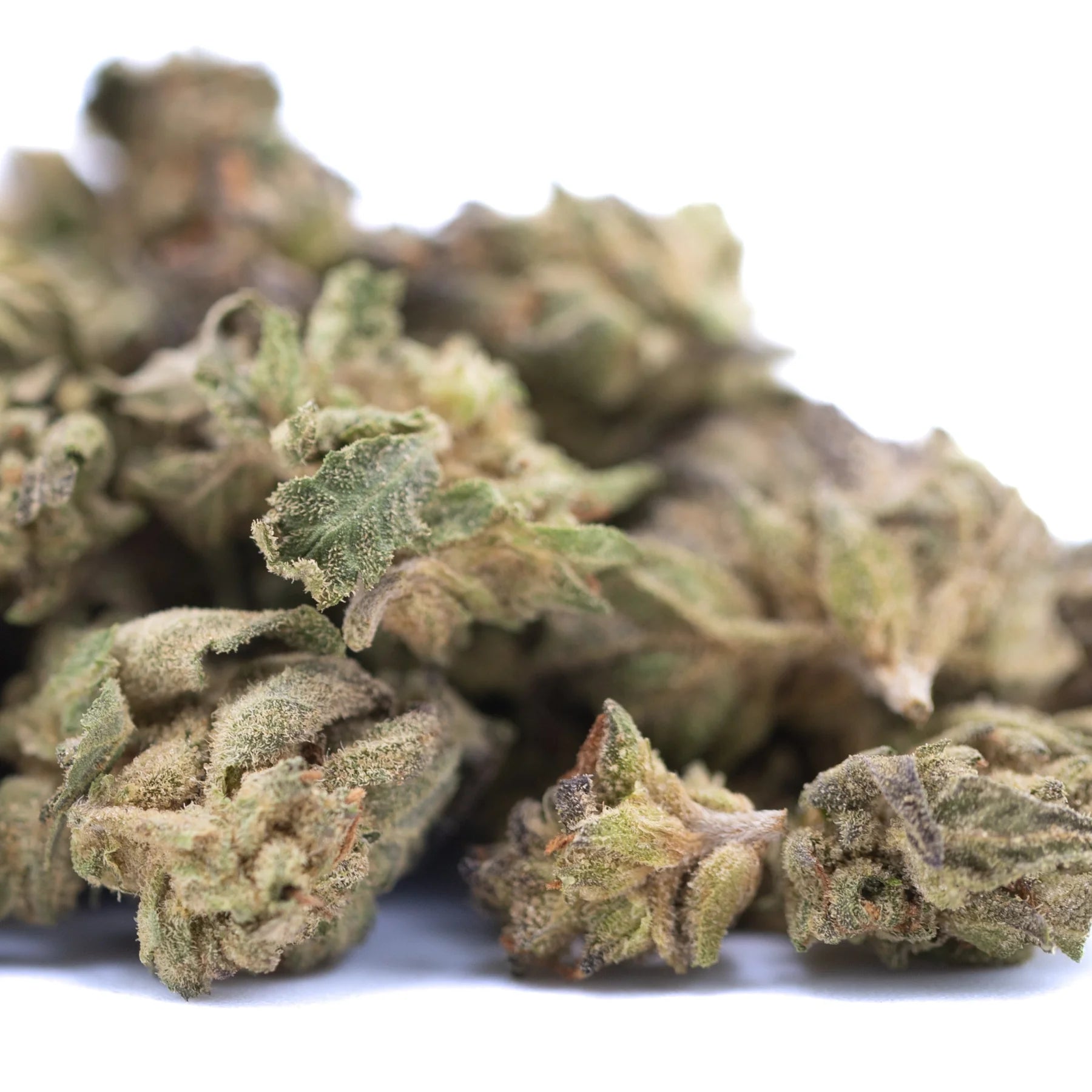 A pile of green rozay cake hemp flower buds with dense trichomes and leaves in greenhouse smalls wholesale packaging