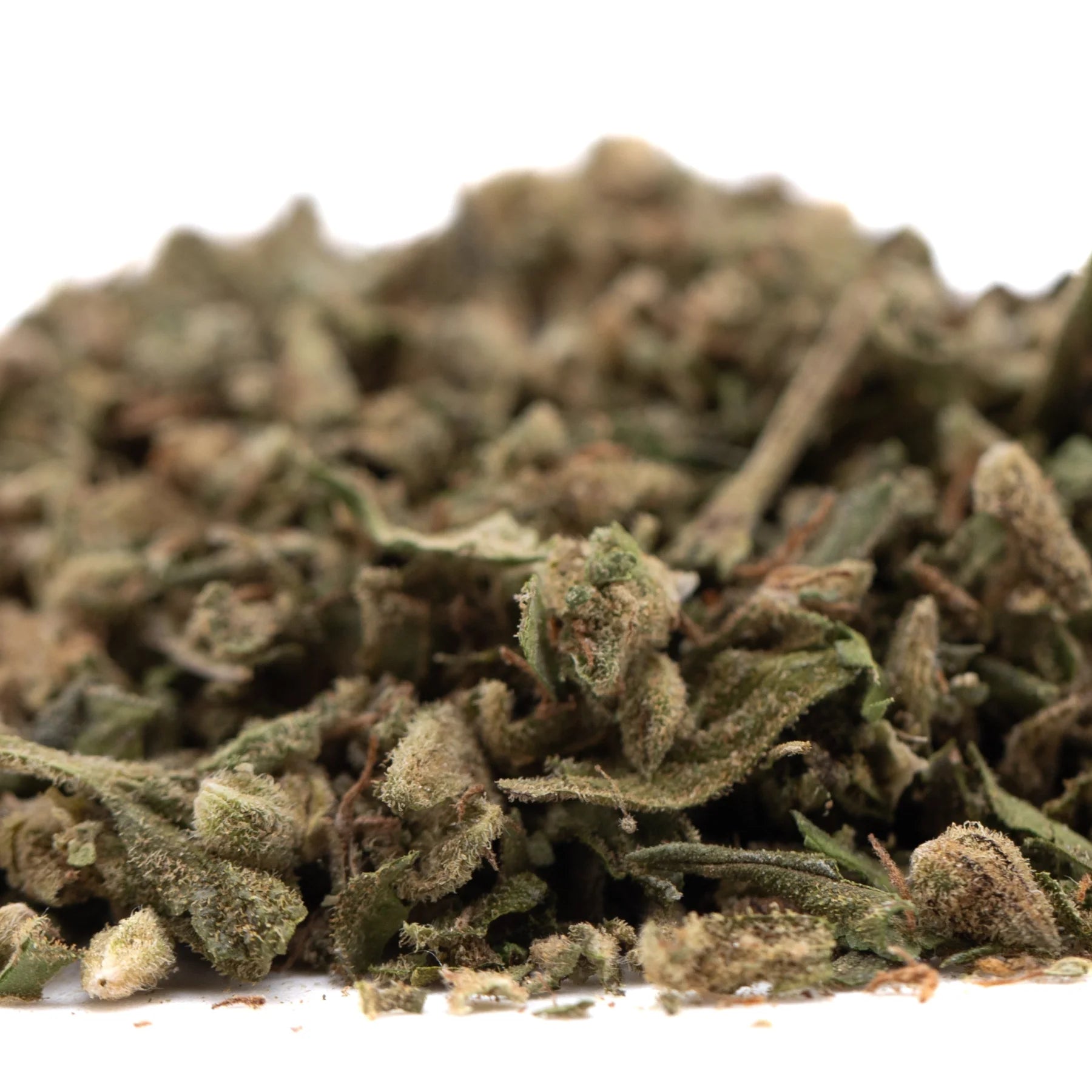 A pile of sour apple full-term thca trim with green and brown hues covered in fine trichomes from legendary genetics