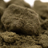 A textured earthy greenish-brown kief full-term cannabis concentrate with a dense crumbly consistency and dessert flavor strawberry cheesecake thca