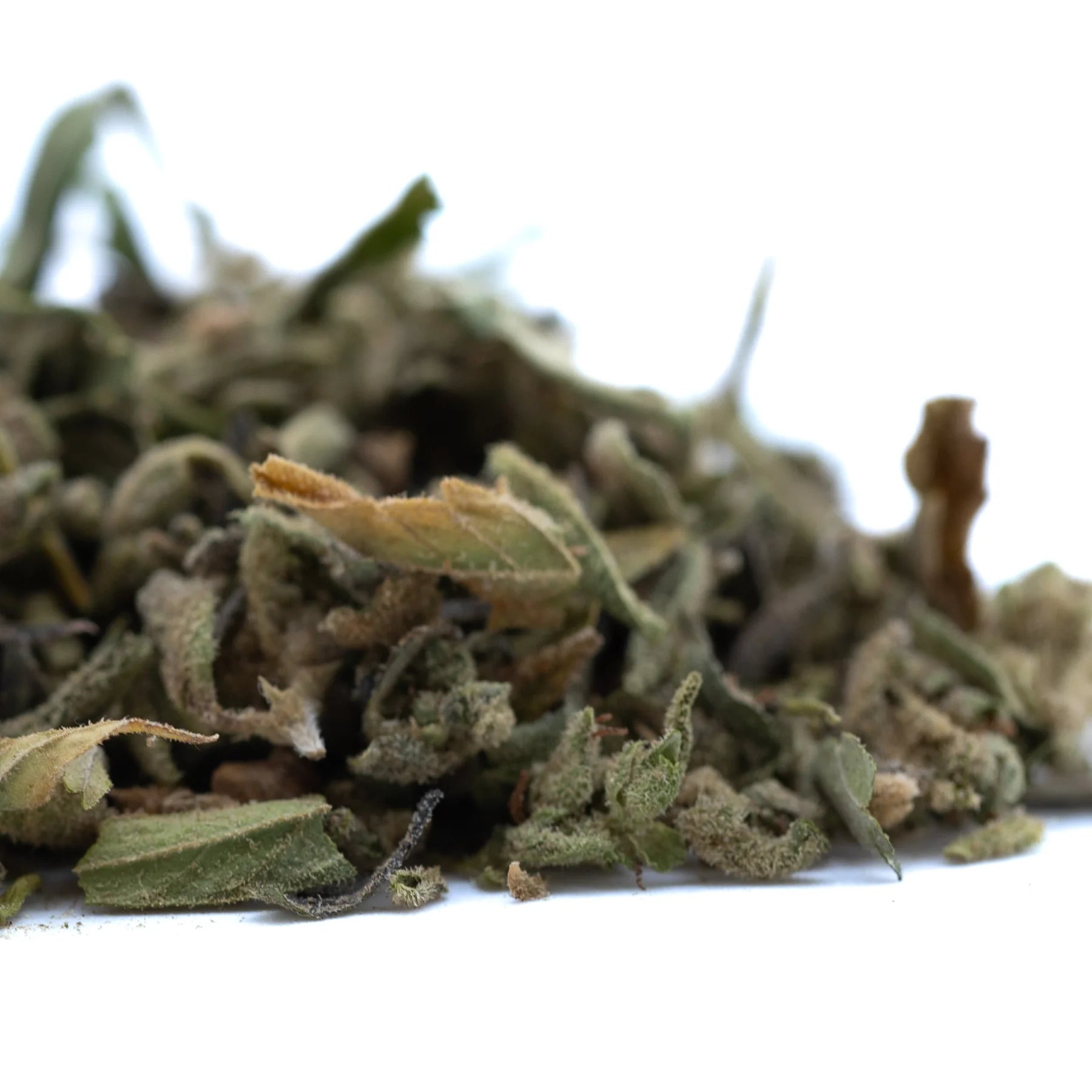A pile of dried greenish-brown turtle taffy thca trim leaves with fuzzy texture showcasing cannabinoid content