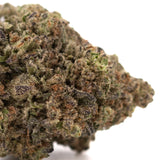 A dense resinous greenhouse thca flower zushi hemp bud with trichomes and green brown purple hues and tropical flavor
